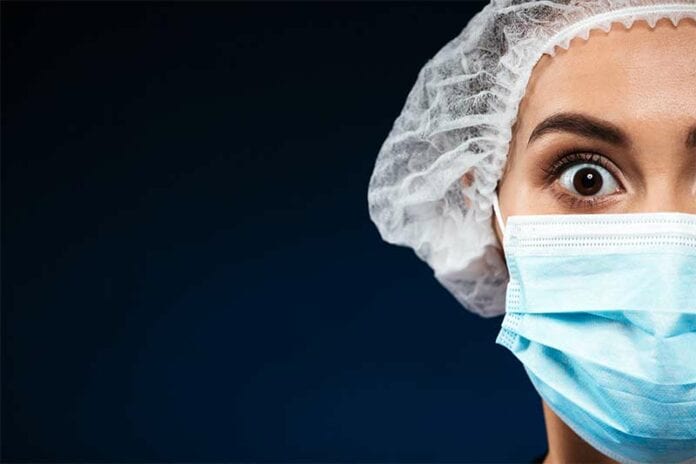 Female nurse wearing mask with facial expression of shock