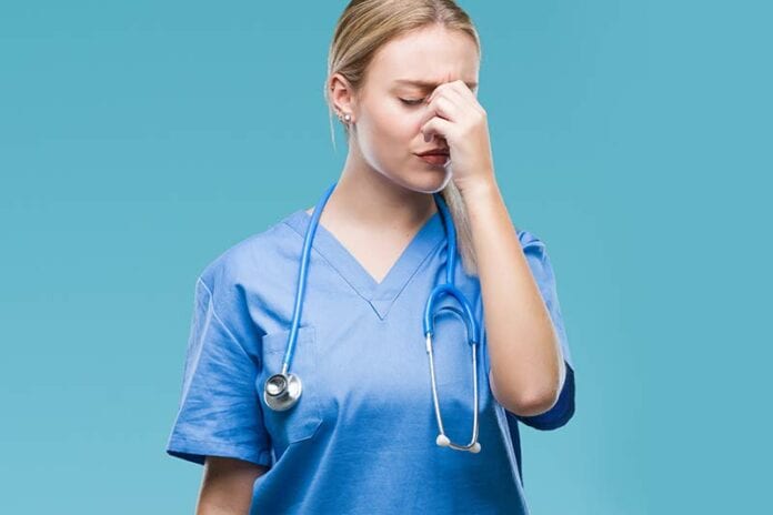 Female nurse in blue scrubs having an allergic reaction at work