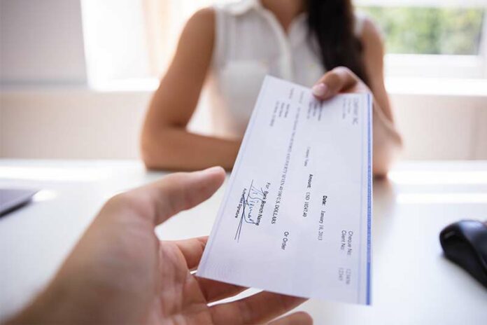 woman handing employee a substantial paycheck
