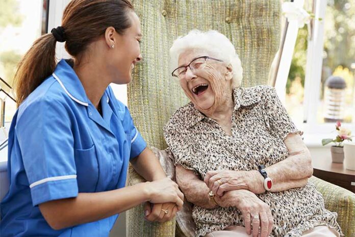 Female nurse in blue scrubs laughing with a patient about whet they said