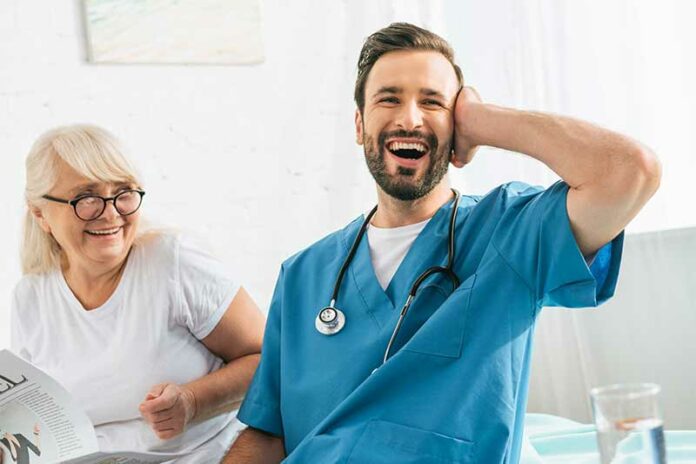 Male nurse in blue scrubs laughing because how hard it can be as a nurse