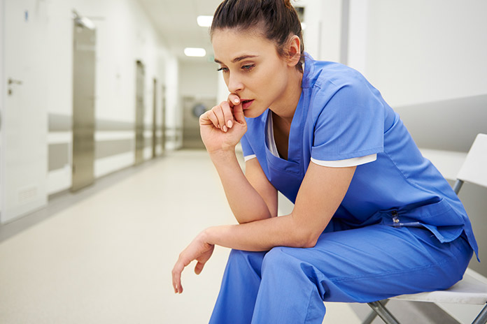 Stressed female nurse in blue scrubs